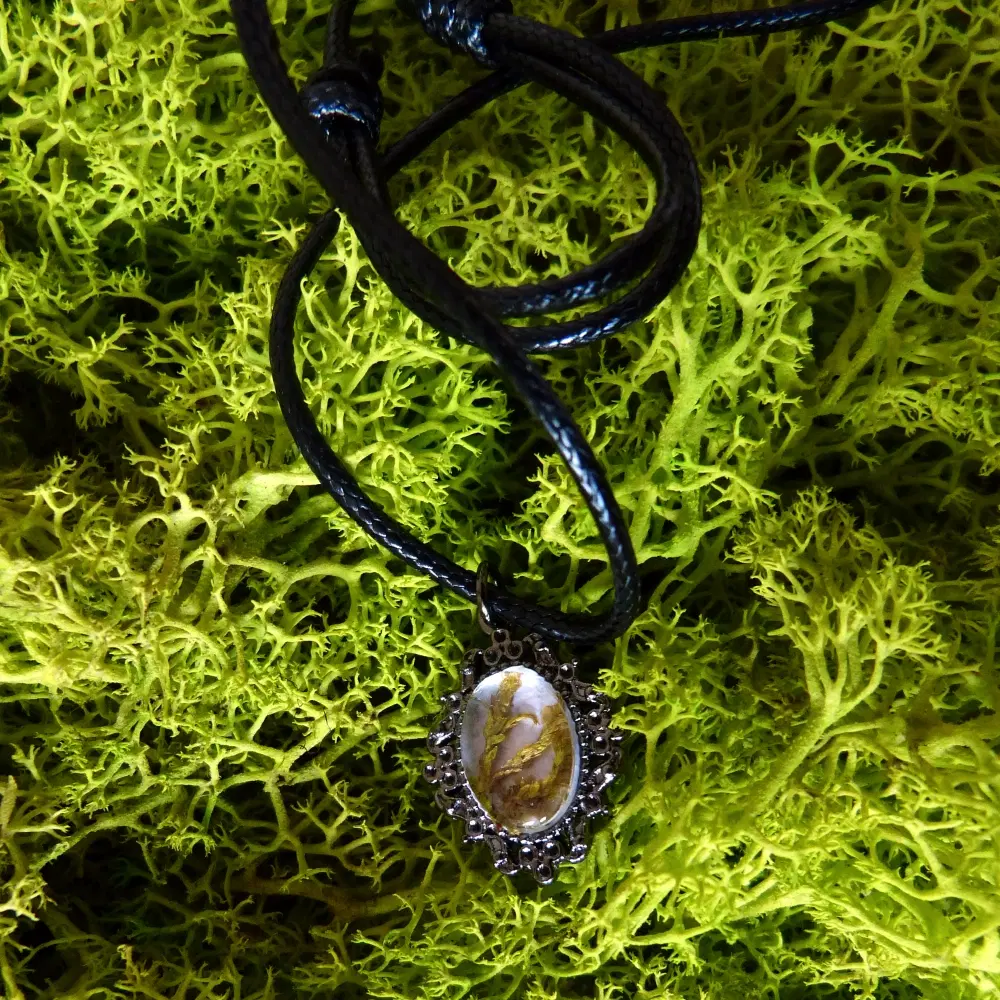 Schwarze Kette mit ovalem Cabochon-Anhänger in dunkler Metallfassung. Im Cabochon ist feines Moos eingeschlossen.
