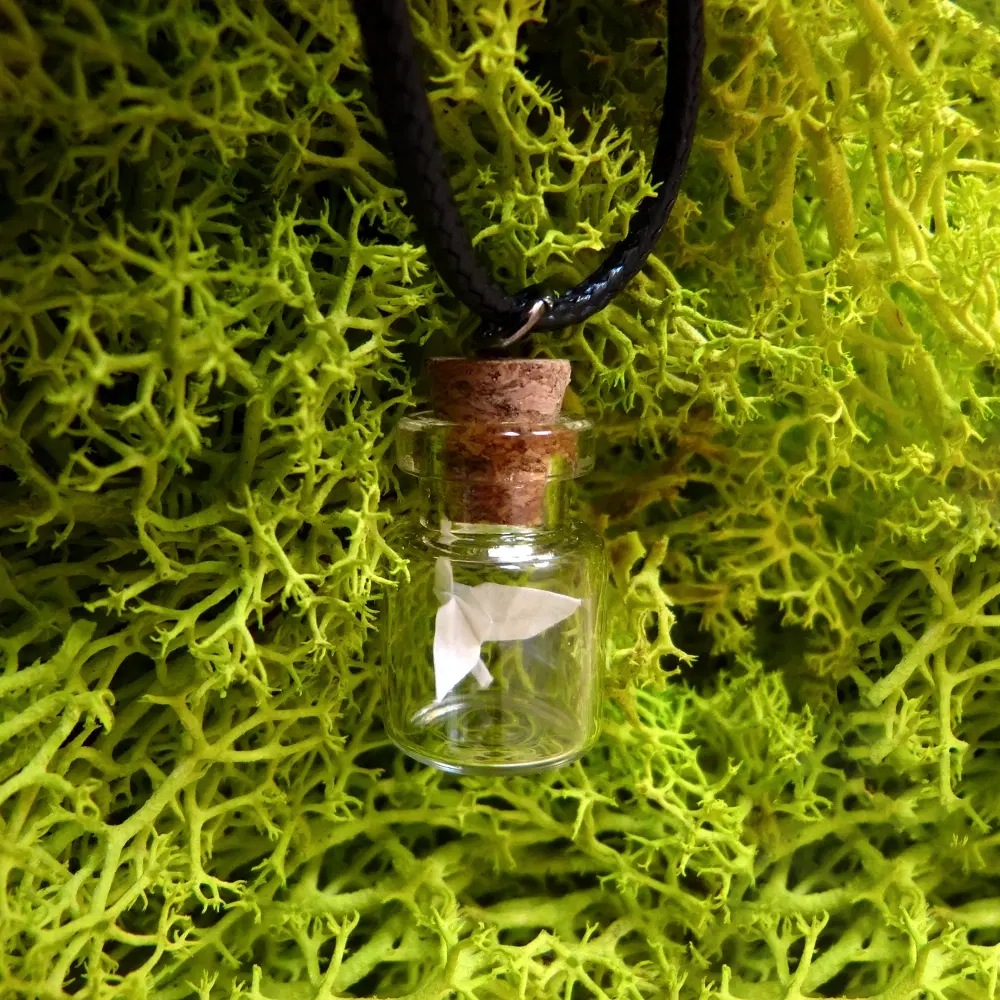 Schwarze Kette mit Anhänger aus einem kleinen Glasfläschchen mit Korken. Im Inneren befindet sich ein gefalteter Origami-Kranich.
